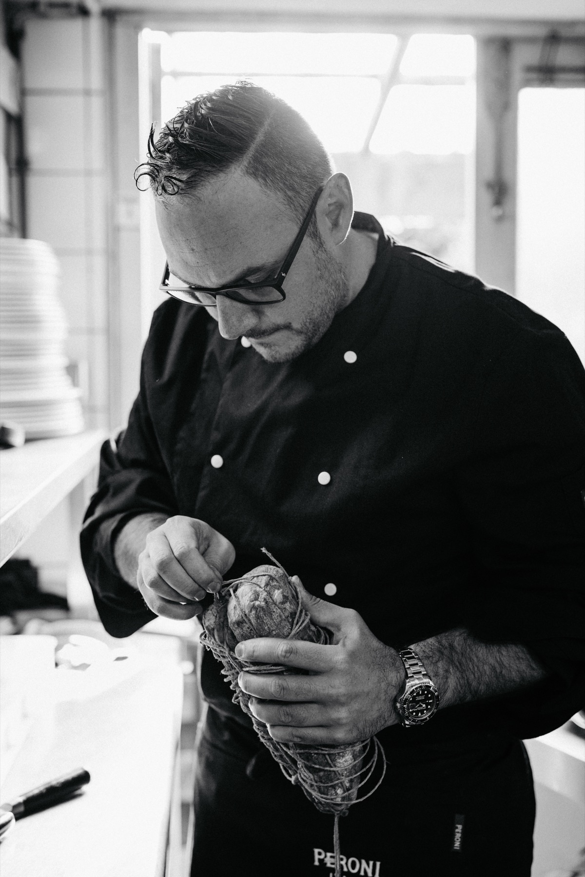 Marco bindt een salame in de keuken van La Salumeria
